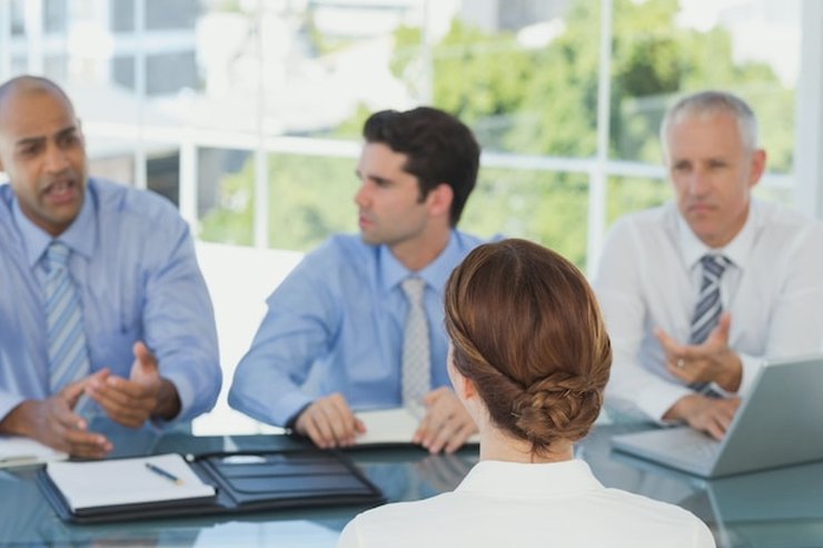 Four people in a meeting around a glass table in a bright office