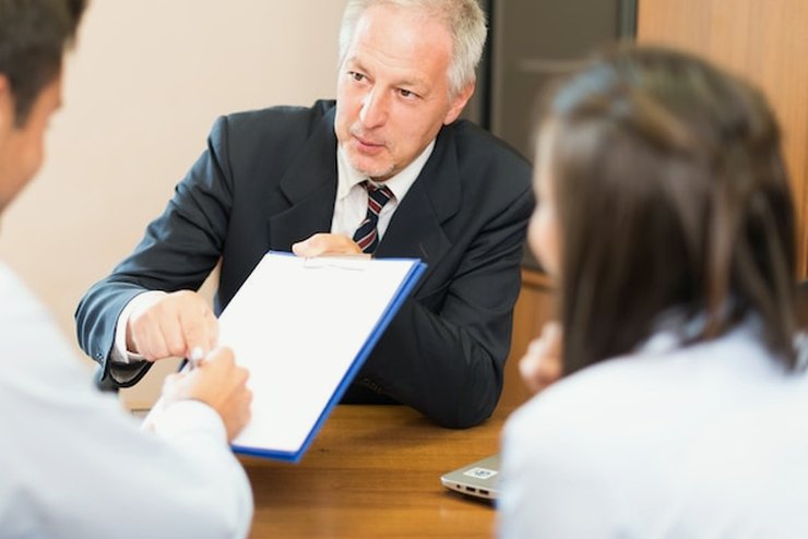 An adviser handing a document across a desk to a client