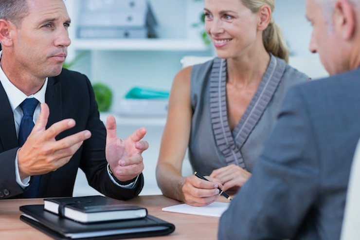 Three people discussing a matter across an office desk