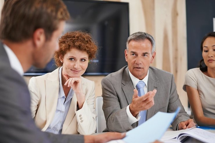 A small team discussing documents around a meeting table