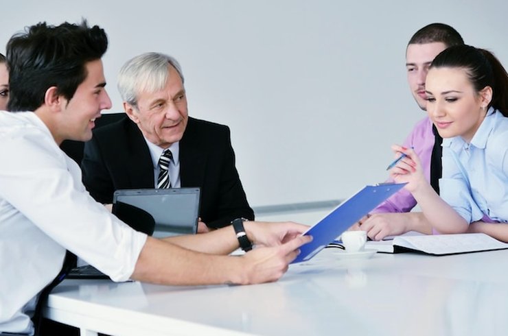 A group reviewing papers together at a white meeting table