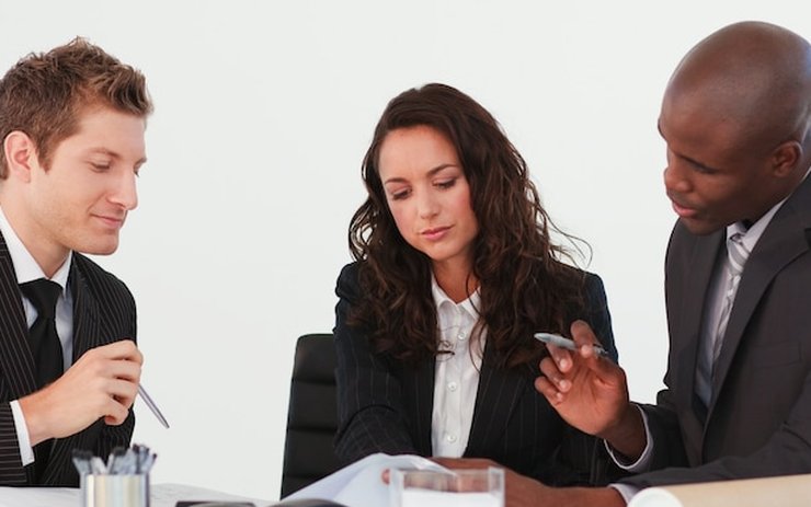 Three colleagues drafting a document together at a desk